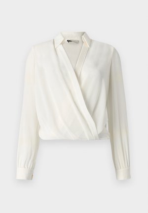 Blouse blanche à manches longues, fabriquée en tissu lisse, avec un col et une texture diagonale subtile.