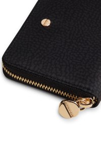 Portafoglio nero con zip realizzato in tessuto testurizzato, dotato di una cerniera in metallo color oro e un innesto decorativo.