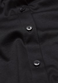 Schwarzes Button-up-Hemd mit glatter Textur, ausgestattet mit vier schwarzen Knöpfen entlang der Vorderleiste und einem subtilen Glanz auf dem Stoff.