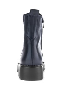 Zwarte leren enkellaars met dikke zool, achterkant treklus en rits aan de zijkant, gezien vanuit de achterkant op een witte achtergrond.