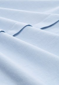 Tela azul claro con una textura suave, presenta patrones sutiles y finos, así como pliegues suavemente drapeados. Ideal para diversas aplicaciones textiles.