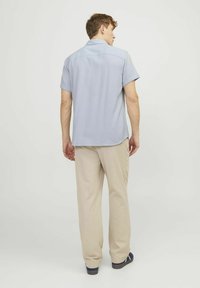 Korteblauw shirt met korte mouwen en een gestructureerd patroon, gecombineerd met beige broek. Het shirt heeft een rechte zoom en een ontspannen pasvorm.
