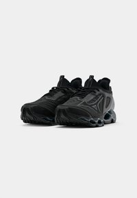 Zapatos deportivos negros con una parte superior texturizada, paneles de malla visibles y una suela moldeada con recortes redondeados para mayor amortiguación.