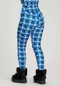 Leggings a scacchi blu e bianchi con una vita alta, realizzati in tessuto elasticizzato, abbinati a stivali neri foderati in pelliccia.