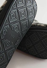 Čierne podrážky papúč so geometrickým vzorom štvorcov a diamantov; obsahujú veľkostné označenie "8/42". Mäkký šedý vrch viditeľný na okrajoch.