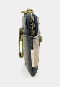 Piccolo portafoglio in pelle nera con zip in ottone e moschettone, che mostra la vista laterale con etichetta in tessuto e foderatura interna beige stampata.