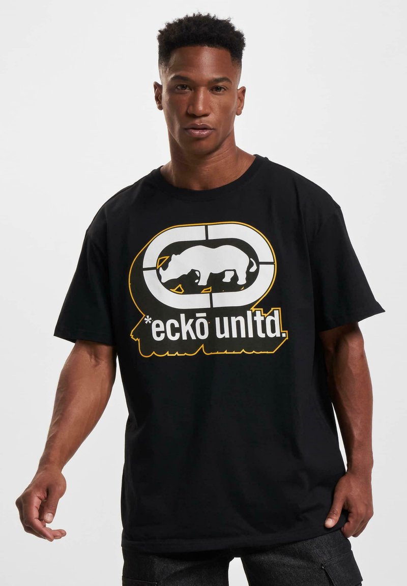 Juodas medvilninis marškinėliai su baltu raganosio grafika ir tekstu "eckō unlted." gelsva spalva. Trumpi rankoviai ir laisvas kirpimas. Paprastas, drąsus dizainas.