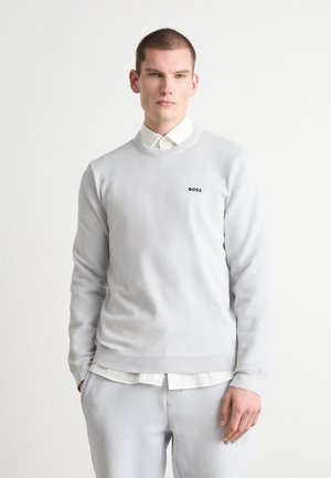 Ljust grå pulloversweater med ribbad textur och rundad halsringning, med en liten svart "BOSS"-logotyp på bröstet.