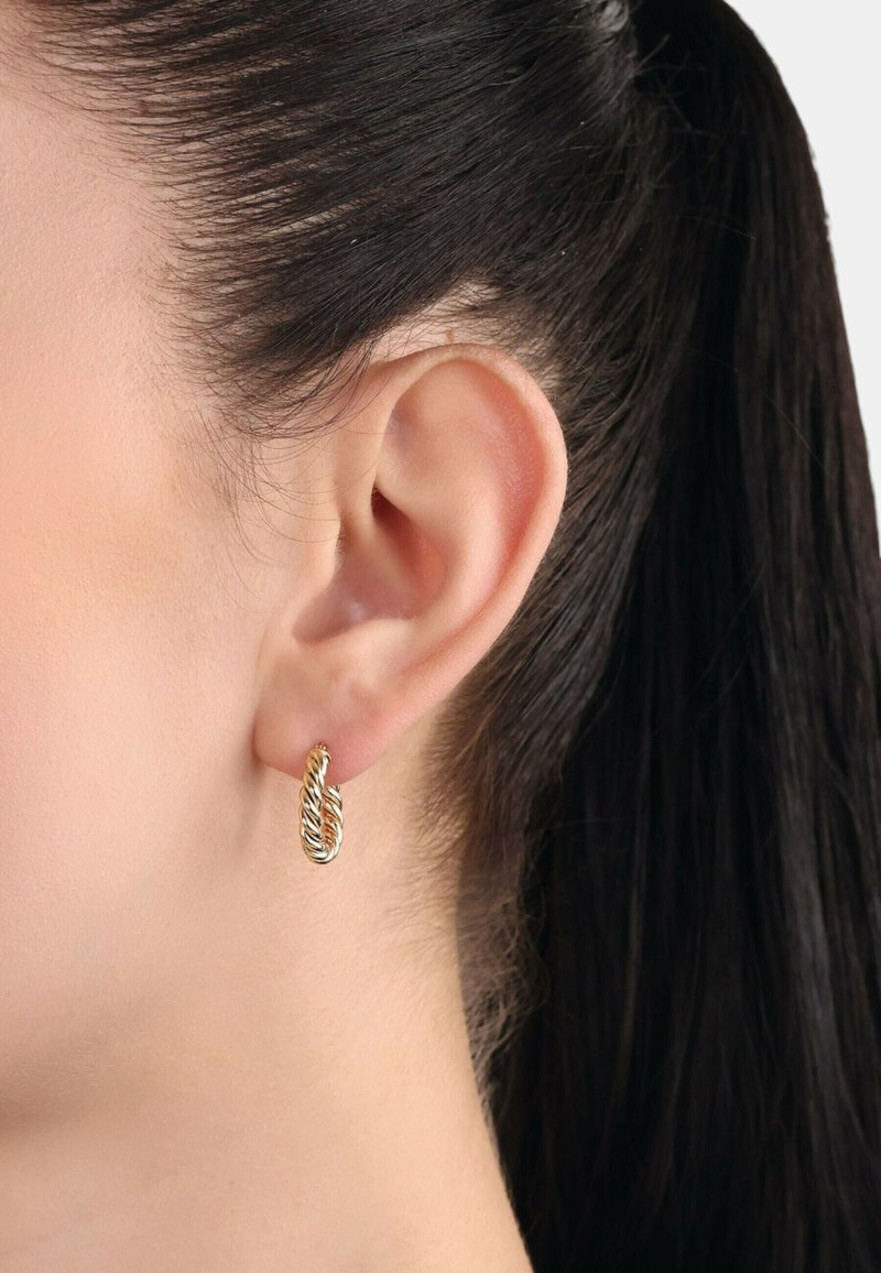 Orecchino a cerchio intrecciato in oro e argento con design a treccia, mostrato su un orecchio con capelli scuri legati indietro. Superficie metallica liscia, finitura lucida.