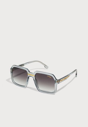 Occhiali da sole rettangolari grigi con lenti sfumate, montatura trasparente e dettagli dorati sulle tempie. Presentano un design audace e geometrico.