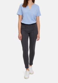 Světle modrý krátký rukáv V-krk top v kombinaci s tmavě šedými elastickými kalhotami s předními švy, úzkým střihem a bílými teniskami.
