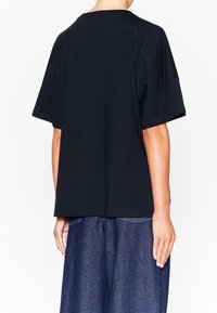 Camiseta de algodón negra con mangas cortas, con un corte relajado y cuello redondo. Textura suave y diseño simple sin patrones visibles.