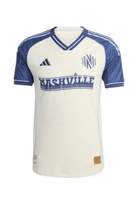 Maillot blanc avec des accents bleus, comprenant un col en V, des manches courtes, et un grand graphique "Nashville" sur le devant. Fabriqué en tissu léger.