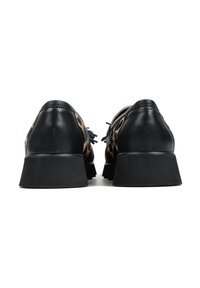 Czarne skórzane buty z wierzchem w panterkę, z niskim, grubym czarnym obcasem i ozdobnymi frędzlami po bokach.