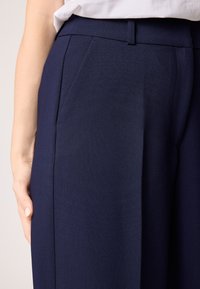 Navyblauwe broek van soepele stof, met zijzakken, een rechte pijp en een aansluitende taille met een discrete sluiting.