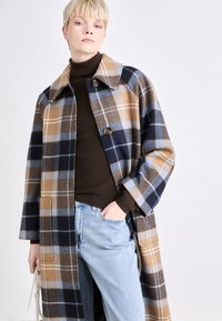 Plaid coat in brown, navy, and light blue. Features a wide collar, button closure, and side pockets. Textured fabric, knee-length design.