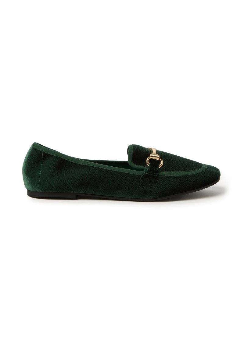 Mocasines de terciopelo verde con punta afilada, que cuentan con una hebilla dorada en la parte frontal y una suela negra plana. Textura suave y diseño elegante.