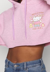 Růžová krátká mikina s kapucí z měkkého materiálu s fialovými šňůrkami, zdobená grafikou Hello Kitty s hvězdami a medvídkovým doplňkem.