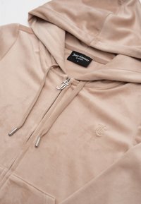 Felpa beige con zip realizzata in tessuto morbido, dotata di cappuccio, tasca frontale e zip con logo argentato, con logo ricamato sul petto.