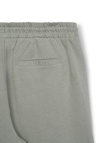 Jogger grigi chiari con vita elastica e una tasca posteriore singola, presentano una texture liscia e morbida e un design semplice e minimalista.