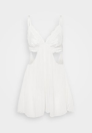 White nightgown with a silky bodice, lace trim on the cups, and cut-out sides, featuring a flowy pleated skirt. Adjustable straps.