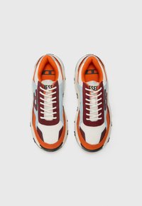 Multicolored sneakers featuring a mesh upper in cream, blue, and red, with orange accents, white laces, and a black rubber sole.