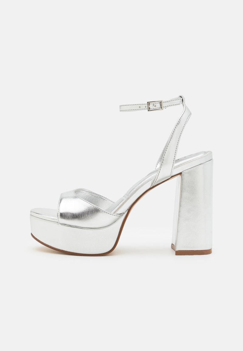 Silver metallic platform sandals with a block heel, open toe, ankle strap, and smooth finish. Designed with a cushioned footbed for comfort.