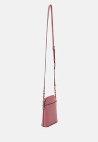 Crossbody bag in textured pink leather, featuring a chain-accented strap and a smooth, rounded top with a zip closure.