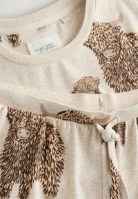Beige katoenen pyjama set met een trekkoord in de taille en dierenprint - afbeeldingen van harige, glimlachende bizons in bruine tinten.