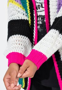 Kleurrijke gebreide cardigan met een losse weving. De hoofdkleuren zijn zwart, wit, roze, paars en groen. Ribgebreide manchetten en een ontspannen pasvorm.
