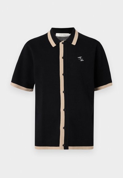 Schwarzes Kurzarm-Polo mit beigem Rippkragen und Knopfleiste, versehen mit einem kleinen gestickten Logo auf der linken Seite.