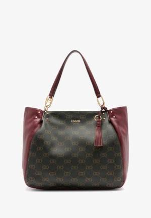 Sac fourre-tout noir et bourgogne en cuir texturé, avec des accessoires en métal doré, un imprimé de logo, une décoration à franges, et des clous sur les côtés. Design spacieux et structuré.