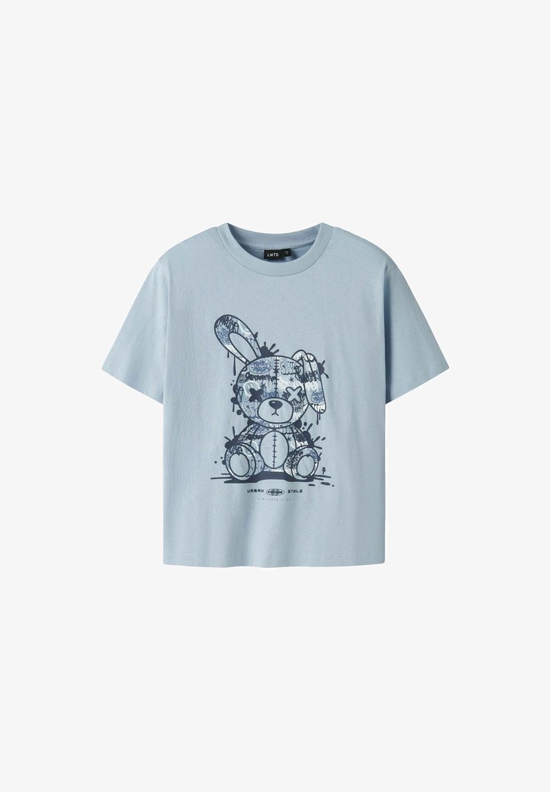 T-shirt bleu clair à manches courtes avec un motif d'ours en peluche cousu en patchwork et le texte "Urban Style" en dessous.