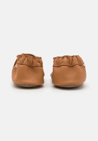 Kůže v barvě tan, slip-on boty s měkkým, nabíraným zadním dílem a plochou hnědou podrážkou. Hladký povrch s minimem švů.