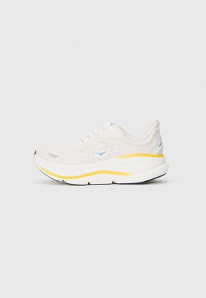 Lightweight running shoe with a beige mesh upper, white midsole, and bright yellow accent. Features padded collar and textured outsole.