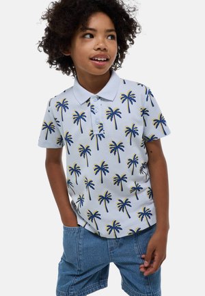 Polo à manches courtes en bleu clair avec un imprimé de palmiers jaunes et marins. Il est doté d'un col et d'une patte de boutonnage à trois boutons. Associé à un short en jean.