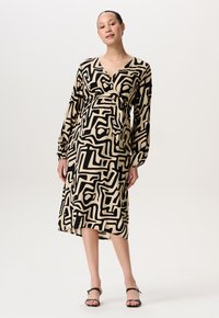 Zwarte en beige gedrukte jurk met lange mouwen, diepe v-hals, getailleerde taille en asymmetrische zoom, met abstracte geometrische patronen.