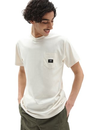 Camiseta de manga corta color crema con bolsillo en el pecho, que presenta una etiqueta del logo de Vans en negro. Está hecha de una tela suave y lisa con un corte relajado.