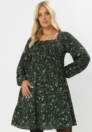 Schwarzes Kleid mit grünem Blumenmuster, ausgestattet mit eckigem Ausschnitt, langen Puffärmeln und gerafftem Oberteil. Ausgestellter Rock mit gestuftem Saum.