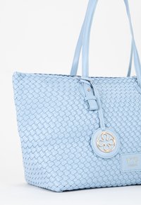 Lichtblauwe gehaakte leren tote bag met dubbele handvatten, gouden ronde hardware-accent en een label met de tekst "V73 Venezia" aan de voorkant.