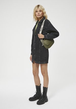 Czarna koszulowa sukienka z denimu z zapięciem na guziki, z długimi rękawami i rozcięciem z przodu. Połączona z oliwkową torebką crossbody i czarnymi botkami typu combat.
