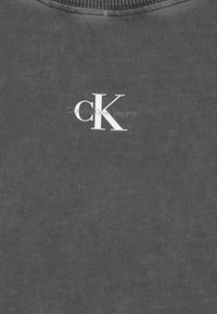 Tmavě šedá mikina s žebrovaným výstřihem, která má bílé logo "CK". Materiál má texturovaný povrch s viditelným tkaním.