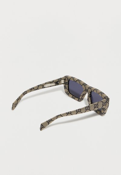 Γυαλιά ηλίου με ορθογώνια μαύρα φακούς και μπεζ βραχίονες και σκελετό διακοσμημένο με επαναλαμβανόμενα σκούρα διπλά λογότυπα G.