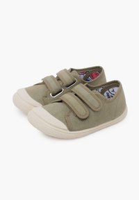 Scarpe in tela khaki con due cinturini in Velcro e suola in gomma. Presentano una punta bianca a contrasto e una fodera interna con motivo.