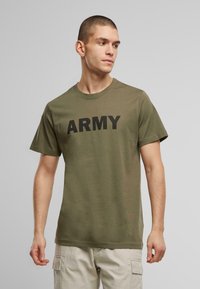 Olivinės spalvos medvilnės marškiniai trumpomis rankovėmis ir apvaliu kaklu, su ryškiu juodu užrašu "ARMY" per krūtinę.