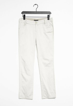 Pantalones de algodón beige con un diseño de corte recto, que cuentan con bolsillos frontales y un cierre de botón en la cintura, colgados de una percha negra.