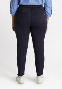 Navy venytät farkut, joissa on muotoiltu malli, joustava vyötärö ja два задних кармана. Helma on hieman revitty. Yhdistetty valkoisiin tennareihin.