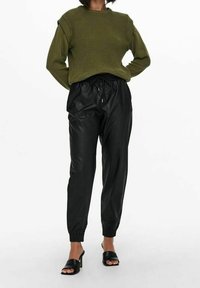 Olijfgroen gebreid trui met geribbelde schouderdetails, gecombineerd met zwarte faux leren joggers met een elastische tailleband en boorden.