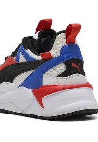 Sznurowany sneaker z czarną, białą i wielokolorową siateczkową cholewką. Posiada czerwone i niebieskie akcenty, teksturowaną podeszwę oraz tylną pętlę do zakładania.