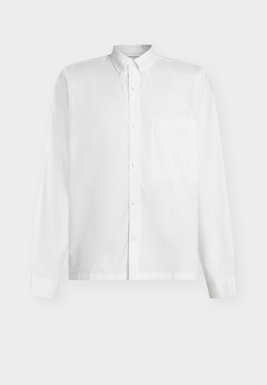 Bijela košulja s dugim rukavima, kopčana na gumbe, s džepom na prsima i okovratnikom s kopčanjem na gumbe na jednobojnoj pozadini.